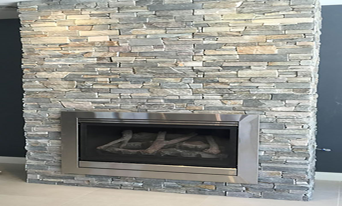 A large modern fireplace in a home surrounded by stone tiles